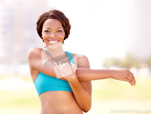 Image of Happy, portrait and black woman stretching arm outdoor for running, training and workout on blurred background. Face, smile and arm stretch by African lady runner in a park for warm up or fitness run