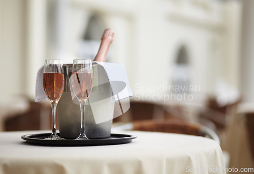 Image of Restaurant, bottle and glasses of champagne on a table for luxury service, celebration and hospitality. Hotel, wealth and wine, alcohol and drinks at a fine dining establishment for an experience