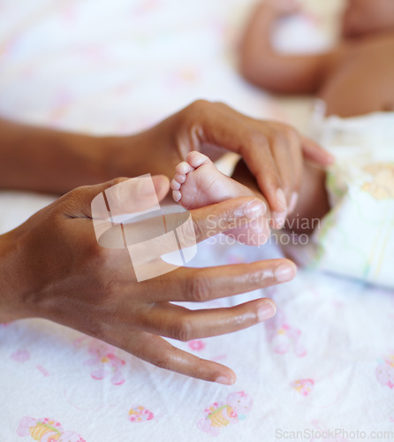 Image of Hands, newborn and closeup of a baby foot with mother rubbing for comfort, care and love. Childcare, cute and zoom of a woman touching her premature infant child feet in her crib at their home.