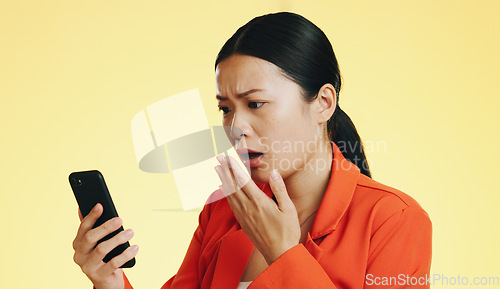 Image of Asian woman, phone and shocked for bad news, loss or disbelief against a studio background. Female face in shock with facial expression on smartphone for terrible text, message or alert on mockup