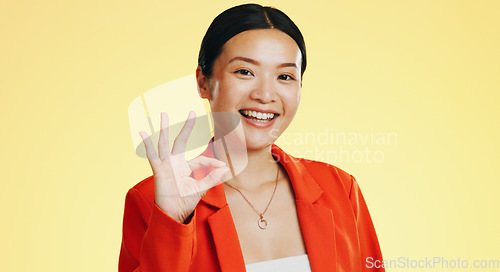 Image of Smile, ok sign and face of Asian woman on yellow background for perfect, good job and agreement. Emoji mockup, hand gesture and portrait of happy girl in studio with success, okay symbol and yes icon