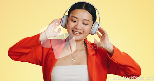 Image of Dance smile, music headphones and Asian woman in studio isolated on a yellow background. Technology, podcast or happy female streaming, listening and dancing to radio, song and audio, sound and album