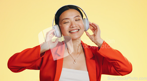 Image of Dance smile, music headphones and woman in studio isolated on a yellow background. Technology, podcast or happy Asian female streaming, listening and dancing to radio, song and audio, sound and album