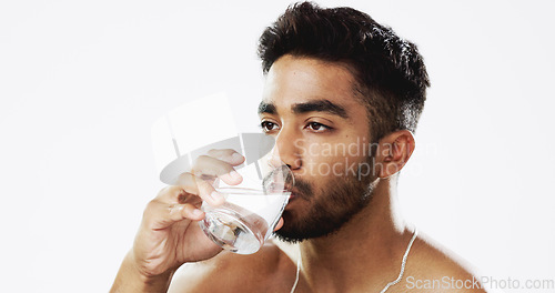 Image of Man drinking water, hydration and health with serious face and glass in hand isolated on white background. Thirsty Indian male in studio, h2o and mineral with healthcare, wellness and mockup space