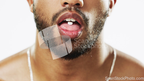 Image of Man, mouth and hands with pill, drug or medication for relief, healthcare or substance abuse against a white studio background. Lips and tongue of male addict taking medical supplement vitamin tablet