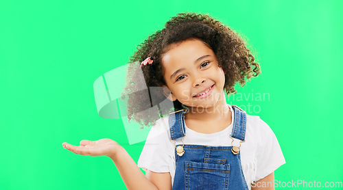 Image of Happy, little girl and green screen with smile for product placement isolated against a studio background. Portrait of cute female kid smiling with palm of open hand showing advertisement on mockup