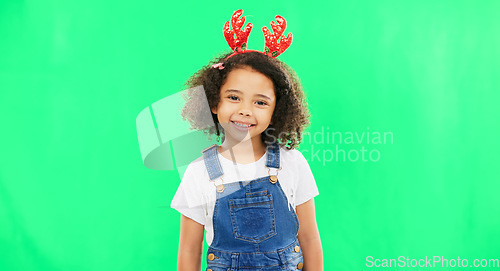 Image of Children, christmas and a girl on a green screen background in studio wearing a reindeer antlers headband. Kids, portrait or festive with an adorable little female child feeling happy in the holidays