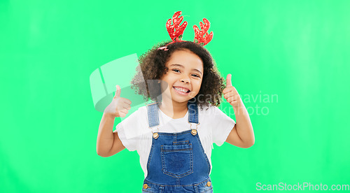 Image of Happy, Christmas and thumbs up with girl in studio for holiday, festive and agreement. Approval, yes and like with child and deer headband on green background for satisfaction, smile and good news