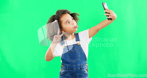 Image of Silly little girl, selfie and peace sign on green screen with goofy facial expressions against a studio background. Female child or kid making funny face with hand sign for photo or vlog on mockup