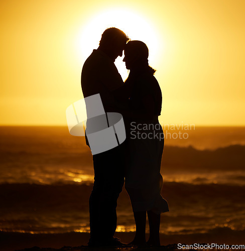 Image of Silhouette, couple and love on a beach at sunset for vacation or holiday outdoor. Romantic man and woman hug in nature with creative sky, space and ocean for care, shadow art and travel or freedom