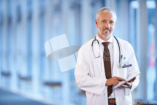 Image of Portrait, healthcare and tablet with a senior doctor standing in a hospital corridor for research or insurance. Medical, trust and technology with a man medicine professional in a clinic for health