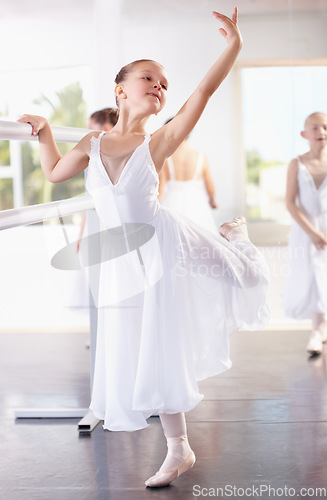 Image of Girl ballerina pose at barre, ballet and dance class with young dancer learning balance and art at studio. Female child in lesson at academy, creativity with fitness and training, elegance and focus