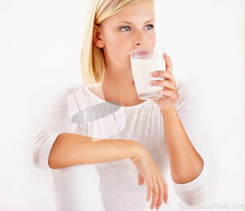 Image of Thinking, milk and calcium with a woman drinking from a glass in studio isolated on a white background. Diet, nutrition and detox with a healthy young female enjoying a drink for vitamins or minerals