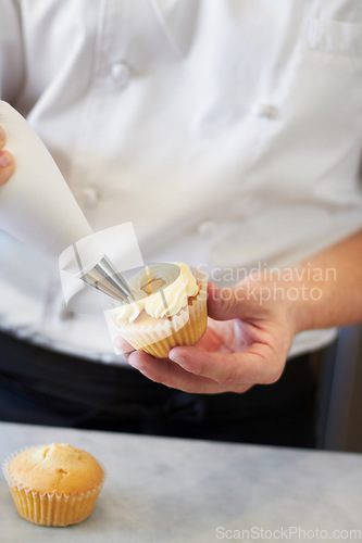 Image of Closeup baker hands, frosting and cupcake for decoration, dessert and cooking with professional chef. Bakery, cream and muffin on table for restaurant, cafe or coffee shop with food for breakfast