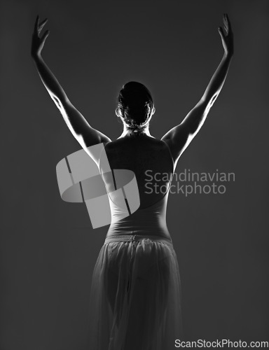 Image of Creative, silhouette and back of a ballerina in a studio with elegant posture, pose or position. Art, monochrome and female ballet dancer doing a classical dance or performance by a black background.