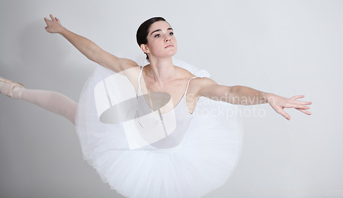 Image of Focus, dance and ballet with a woman in studio on a white background for rehearsal or recital for theatre performance. Art, creative and balance with an elegant young ballerina or dancer in uniform