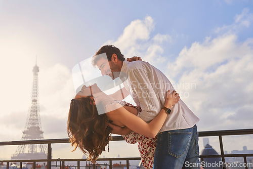 Image of Love, Paris and couple together for a kiss, romantic time or balcony of apartment, hotel with Eiffel Tower in background. Partner, woman and man in France for vacation, travel or honeymoon holiday