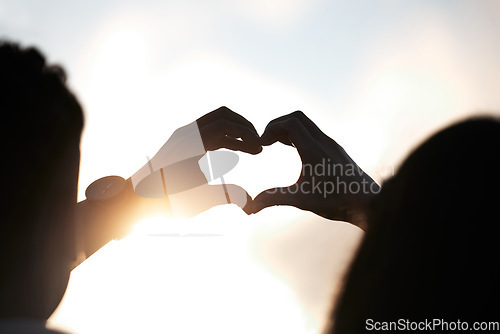 Image of Heart hands, sky and couple at sunset, emoji in silhouette and nature to celebrate marriage, date or honeymoon. Summer, travel and vacation, love hand sign with man and woman together in relationship