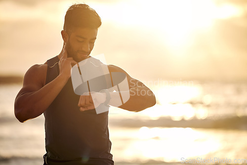 Image of Sunset, beach and man with smart watch for heart rate tracker, fitness and workout in nature. Exercise, ocean and runner mobile app checking pulse or time on stopwatch in silhouette with mockup space