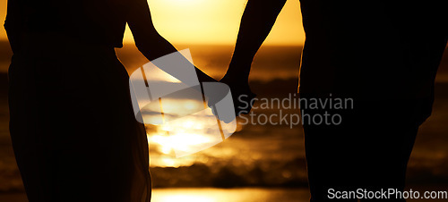 Image of Silhouette, couple and holding hands at sunset on beach for vacation or holiday outdoor. Behind man and woman in nature with creative art, space and ocean for love, shadow and travel or freedom