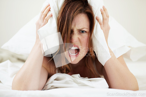 Image of Portrait, angry and woman with pillow on ears to block noise, loud sound and sleep fail on bed in home bedroom. Face, person and covering head with cushion for insomnia, tired and frustrated scream.