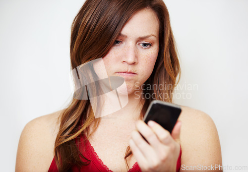 Image of Phone, text message and an angry woman in studio on a white background unhappy while reading bad news. Social media, internet and app with a young female looking upset while checking her mobile inbox