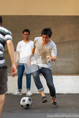 Image of Friends in city street, man with football for sports, fun and happy energy with urban games in Korea. Game, friendship and group of young Asian men running in road with soccer ball for weekend time.