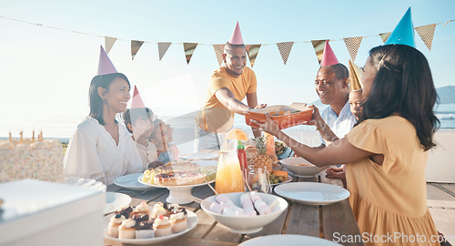 Image of Birthday, parents and children with food by beach for event, celebration and party outdoors. Family, social gathering and mother, father with kids at picnic with cake, presents and eating together