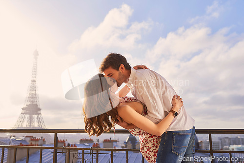 Image of Paris, love and couple together for a kiss, romantic time or balcony of apartment, hotel with Eiffel Tower in background. Partner, woman and man in France for vacation, travel or honeymoon holiday