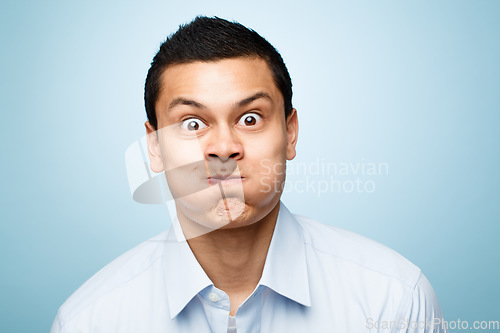 Image of Comic, portrait of man with blowing cheeks and against a blue background. Blown mouth or mockup, surprised or fun and isolated male person with funny face expression against a studio backdrop