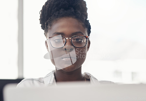 Image of Black woman, entrepreneur and focus on computer at the office for online search for business. Professional female, tech and working with serious face for a project on the internet for a start up.