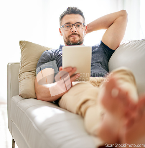 Image of Tablet, sofa and man relaxing at his home reading a ebook or online blog on the internet. Rest, browsing and mature male person watching a video on social media with digital technology in living room