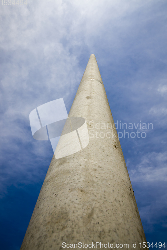 Image of long concrete electric pole against the blue sky, close-up