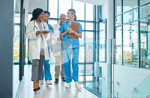 Image of Hospital, doctors and nurses team walking with a tablet for a discussion, planning or research. Diversity men and women healthcare group talking about medical strategy, virus or surgery schedule