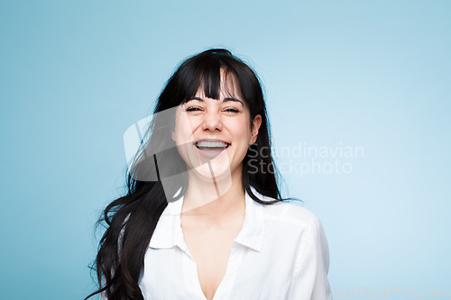 Image of Smile, laughing and portrait of a beautiful woman isolated on a blue background in a studio. Happy, young and a headshot of a girl in a shirt with confidence, empowerment and looking stylish