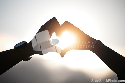 Image of Heart hands of couple at sunset, emoji in silhouette and nature to celebrate marriage, date or honeymoon. Summer, travel and vacation sun, love hand sign with man and woman together in relationship.