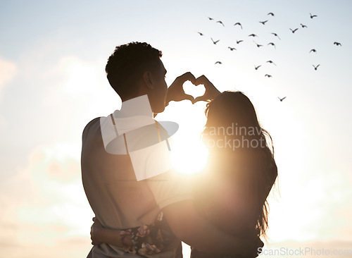 Image of Couple at sunset sky, heart hands in silhouette and nature to celebrate marriage, date or honeymoon. Summer, travel and tropical vacation, love hand sign with man and woman together in relationship.