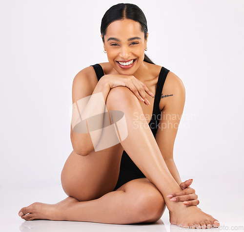 Image of Woman, underwear and healthy body in studio portrait with smile, sitting and happiness by white background. Girl, model and young with beauty, lingerie and glow on skin with excited face on floor