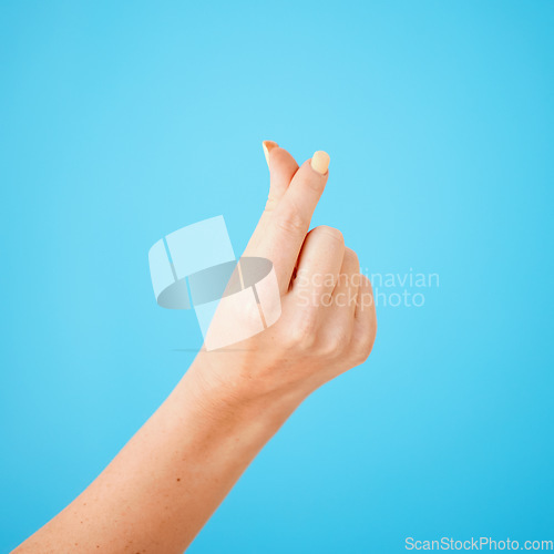 Image of Gesture, hand sign for cash and money closeup on studio blue background for expensive, finance or currency. Person, thumb and index fingers rubbing together or symbol to pay, payment or poor salary