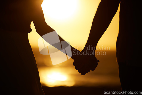 Image of Holding hands, couple and silhouette on beach at sunset for vacation or holiday outdoor. Behind man and woman in nature with peace, calm and ocean for love, creative shadow and travel or freedom