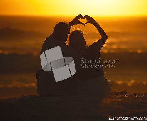 Image of Silhouette, couple and heart shape at sunset on beach for vacation, holiday or emoji outdoor. Back of man and woman in nature with creative sky, hand icon and ocean for love, art and travel freedom