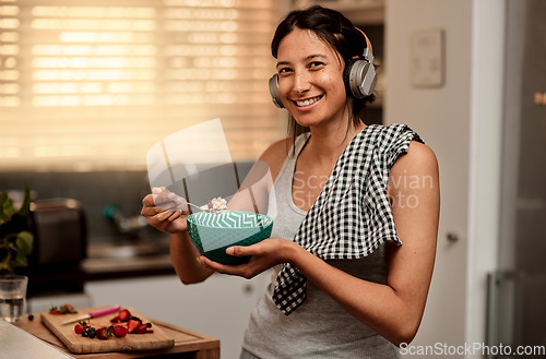 Image of Headphones, eating breakfast and portrait of woman in kitchen with strawberry. Face headphone, food and happy female person with healthy fruit while listening to audio music, sound or radio podcast.