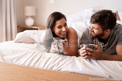 Image of Bed, coffee cup and happy couple bonding, relax and enjoy morning latte, home drinks or hydration beverage. Comedy, funny and romantic man, woman or people with tea, love and laughing at bedroom joke