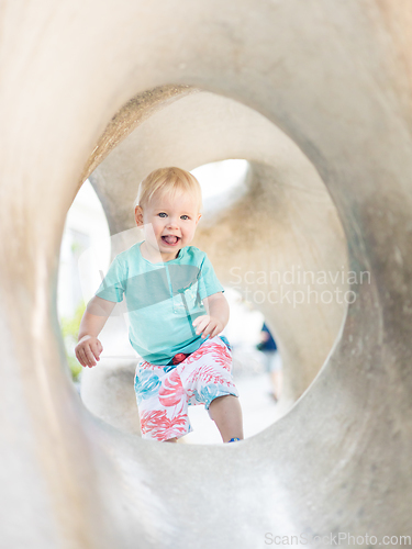 Image of Child playing on outdoor playground. Toddler plays on school or kindergarten yard. Active kid on stone sculpured slide. Healthy summer activity for children. Little boy climbing outdoors.