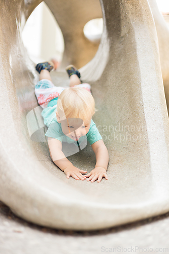 Image of Child playing on outdoor playground. Toddler plays on school or kindergarten yard. Active kid on stone sculpured slide. Healthy summer activity for children. Little boy climbing outdoors.