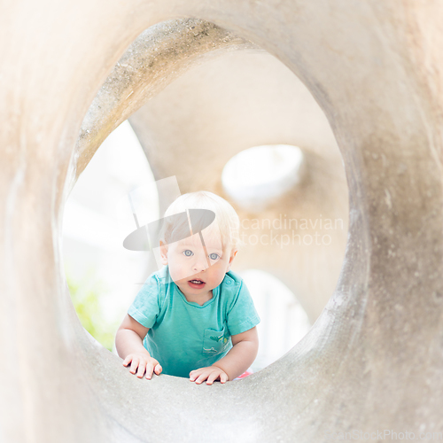 Image of Child playing on outdoor playground. Toddler plays on school or kindergarten yard. Active kid on stone sculpured slide. Healthy summer activity for children. Little boy climbing outdoors.