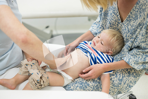 Image of Infant baby boy child being examined by his pediatrician doctor during a standard medical checkup in presence and comfort of his mother. National public health and childs care care koncept.