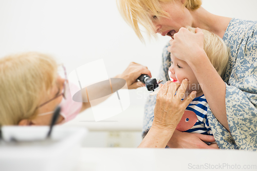 Image of Infant baby boy child being examined by his pediatrician doctor during a standard medical checkup in presence and comfort of his mother. National public health and childs care care koncept.