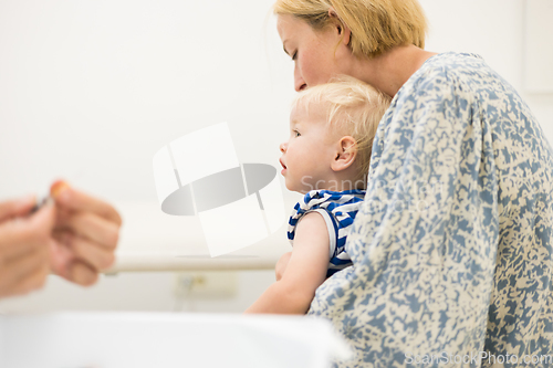 Image of Child beeing vaccinated by pediatrician in presence of his mother. Preventive vaccination against Diphtheria, whooping cough, tetanus, hepatitis, haemophilus influenzae, pneumococcus, poliomyelitis