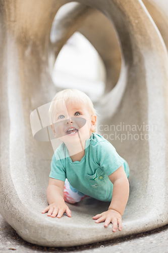 Image of Child playing on outdoor playground. Toddler plays on school or kindergarten yard. Active kid on stone sculpured slide. Healthy summer activity for children. Little boy climbing outdoors.